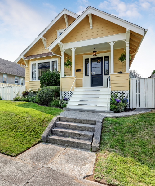 A yellow house with white trim and a black door