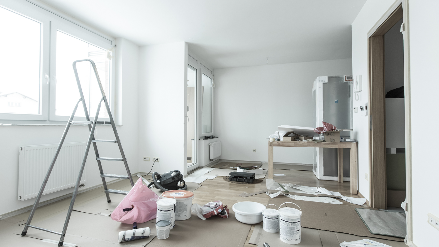 A room with a ladder, paint cans, and other items on the floor