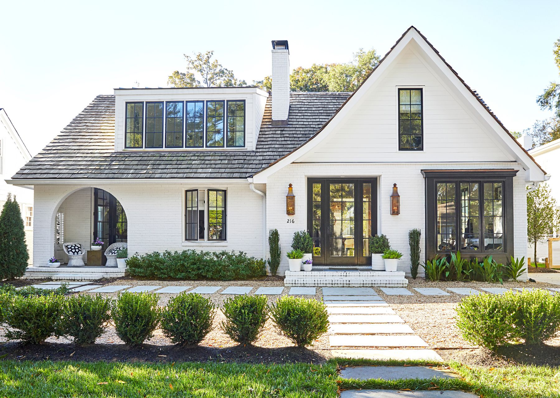 White modern farmhouse with black-trimmed windows and landscaped front yard