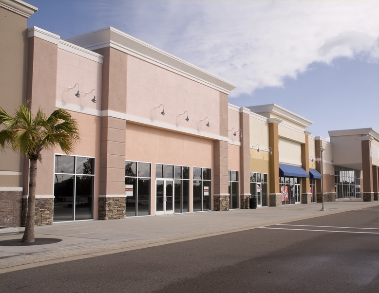 Empty strip mall with palm tree, new commercial storefronts and parking lot